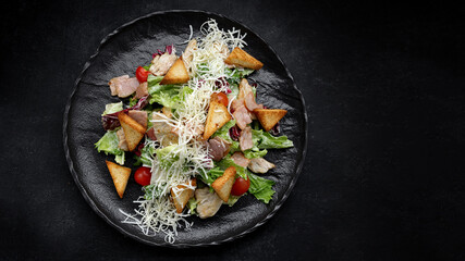 Caesar salad on a black plate. Horizontal