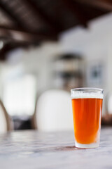 A freshly poured beer sits on a table in a well-lit room.
