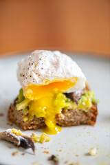 Healthy breakfast from poached egg, smashed avocado, grilled mushrooms on sourdough bread toast, half eaten, selective focus, shallow DoF