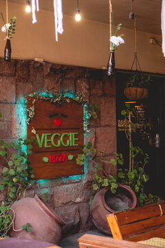 Veggie Pizza restaurant entrance with beautiful plants, rustic decoration and green lights in the afternoon