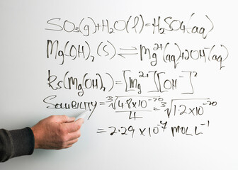 Mans hand writing mathematical equation on whiteboard