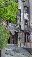 Bucha, Ukraine - May 22, 2022: Russia's aggression against Ukraine. Facade of the building and stairs after tank shots. Destroyed building. Stairs of an abandoned house. House exterior