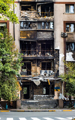 Fototapeta na wymiar Bucha, Ukraine - May 22, 2022: Russia's aggression against Ukraine. Facade of the building and stairs after tank shots. Destroyed building. Stairs of an abandoned house. House exterior