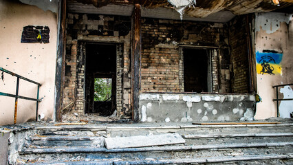 Fototapeta na wymiar Bucha, Ukraine - May 22, 2022: Russia's aggression against Ukraine. Facade of the building and stairs after tank shots. Destroyed building. Stairs of an abandoned house. House exterior