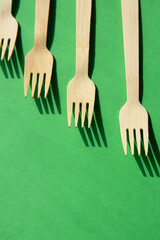 Wooden bamboo cutlery on bright green background