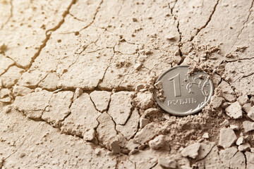One coin of the Russian ruble lies on the surface of the cracked sand