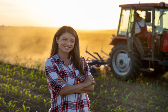 Farmer woman posing in front of tractor in field