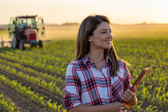 Farmer woman posing in front of tractor in field