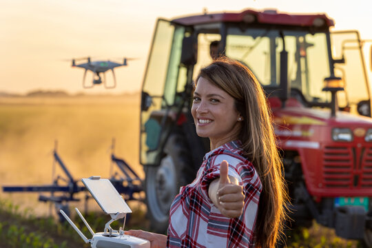 Farmer woman driving drone in field and showing OK sign