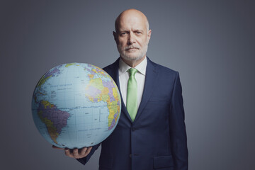 Corporate businessman holding a globe - obrazy, fototapety, plakaty