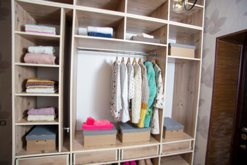 Big wardrobe with different clothes and accessories in dressing room