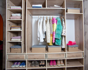 Big wardrobe with different clothes and accessories in dressing room