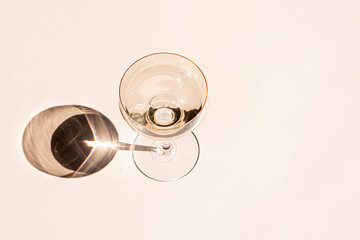 Cocktail glass with drinks on the light table in natural sunlight with shadows. Minimalist creative summer drinks composition. Flat lay, top view image.