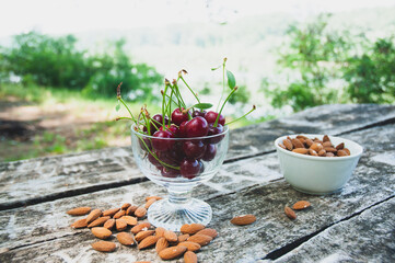 Cherries and almonds on a wooden table in the forest.