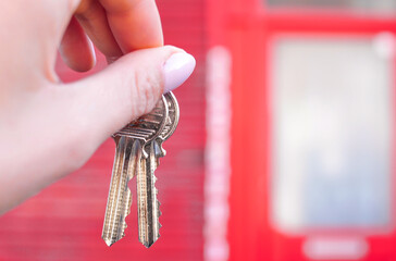 Woman's hand with metal keys on blurred background with house. High quality photo