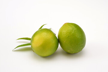two whole fresh limes on a white background