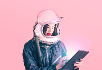 Isolated on white background. Cute girl studying information in the tablet. Astronaut girl in a space suit. Free space for text. Space helmet. White isolated. Space girl. © Kseniya Iv