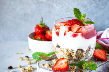 Parfait with cream or yogurt, jam and fresh strawberries in the glass jar.