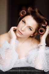 beauty concept. portrait of a beautiful young showy brunette woman with bright pin-up make-up in pink curlers. Studio Shot, Cropped. Facial treatment . Cosmetology , skin care and spa