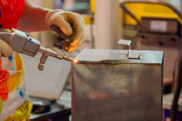 Close up: welder hands using portable handheld laser welding machine. Manufacturing, industrial,...