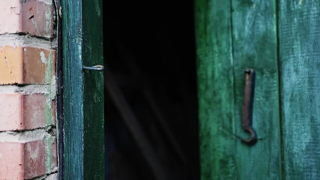 Caucasian man's hand opens a wooden door in a house locked on a hook. 