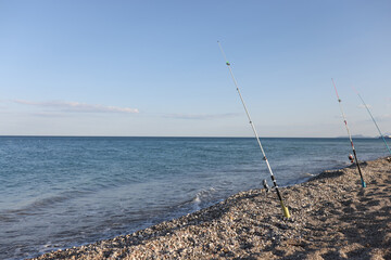 Fototapeta na wymiar Fishing rods on sea beach, seaside landscape