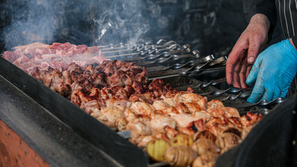 Cooking shish kebab on skewers. Meat, vegetables and bread rolls baked on coals.A male chef roasts juicy beef, chicken, pork.The concept of street food. Grilled meat on the grill.Meat on the barbecue.