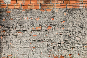 Wall mute with plaster and some exposed bricks, with signs of time, highlighting its texture.
