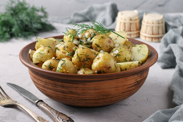 Potato salad with mustard, dill and garlic in a brown bowl on a gray background