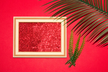 retro frame with glitter red wallpaper as copy space, next to it palm and jungle leaves, creative summer romantic design