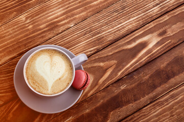 purple cup of coffee with macaroons on the wooden background