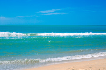Blue sea with a wave and a sandy shore, on the horizon with a blue sky. Seascape in summer