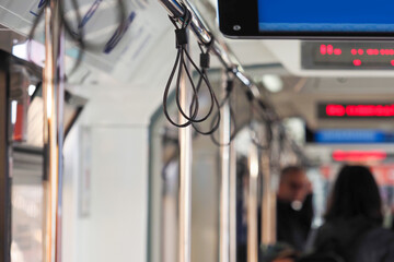 Public city transport, lot of unrecognizable people. Illuminated information boards, hold loops