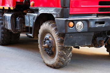Red truck on asphalt road. Low angle view of wheels of heavy large truck