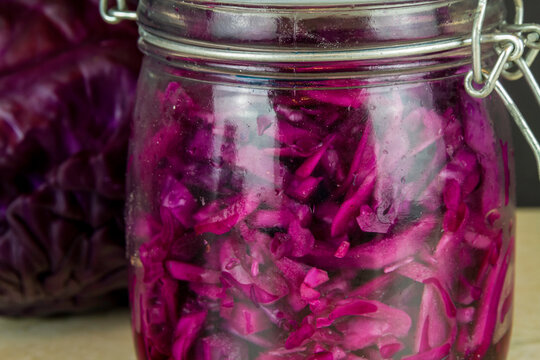 Red cabbage sauerkraut with cabbage behind close up.