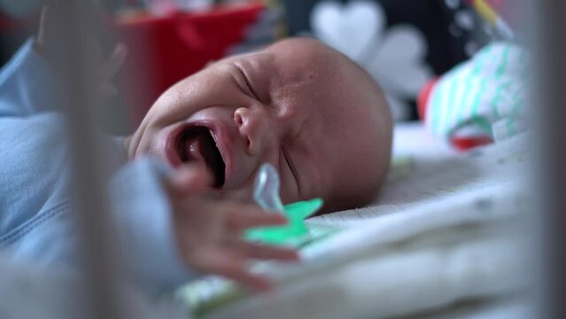 Newborn lost the pacifier and crying in his bed