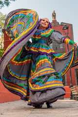 Young Mexican woman in a traditional folklore dress of many colors, traditional dancer.