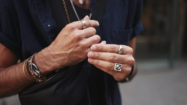 Close-up of male hands in bracelets and rings. Man adjusts the ring on his finger. Guy twists the ring on his finger