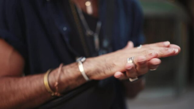 Close-up of male hands in bracelets and rings. Man rubs his palms together. Guy adjusts bracelets on hand