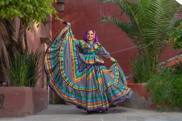 Young Mexican woman in a traditional folklore dress of many colors, traditional dancer.