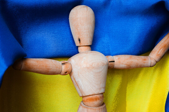 Wooden figurine of a man holding the Ukrainian flag. The concept of war 2022 between Ukraine and Russia.
