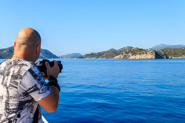 Travel photographer man with professional camera taking photos of the Mediterranean Sea in Antalya province, Turkey