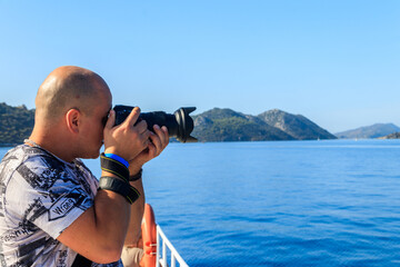 Obraz premium Travel photographer man with professional camera taking photos of the Mediterranean Sea in Antalya province, Turkey