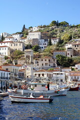 Fototapeta na wymiar Boats in the harbor, below the city of Hydra, Greece, rising up on a hill above