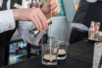 Closeup of a bartender's hands pouring cocktail.