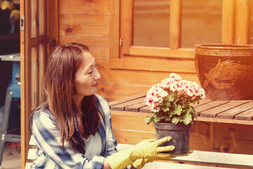 Woman hands wearing yellow gloves holding and planting flowers
