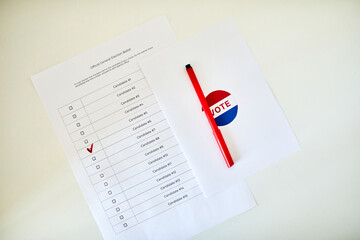 Top view closeup of voting ballot with marked box and red pen on white table, copy space