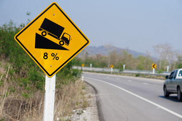 Yellow traffic sign  to warn  truck driver to drive carefully down to hill on slope a steep 8 percent(8%) downhill gradient beside the road.  Concept : Traffic Road Sign and symbol.            