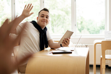 Online lesson male student studying at college uses a laptop, video chat, sits in a lecture hall