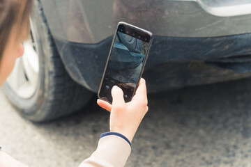 Insurance concept. Outdoor close-up shot of a caucasian woman taking a picture of a front fender...